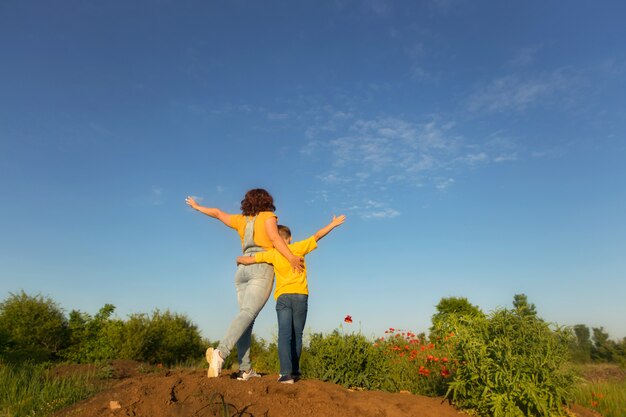 Mãe de família feliz e filho bebê no verão na natureza ao pôr do sol