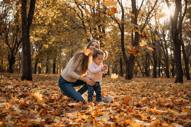 Mãe de família feliz e menina brincando ao ar livre no parque de outono menina e sua mãe em