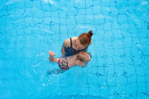 Foto mãe de família feliz ensina a filha de anos a nadar na vista de cima da piscina