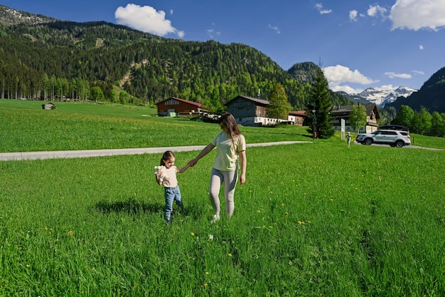 Mãe de mãos dadas filha e andando no prado alpino em Untertauern Áustria