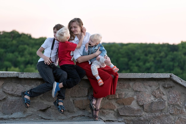 Mãe de muitos filhos com filhos na superfície da natureza. Férias com crianças.