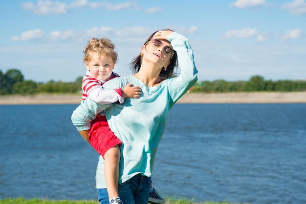 Mãe de mulher adulta com filho menino se divertindo no parque Mãe segura o filho nos ombros