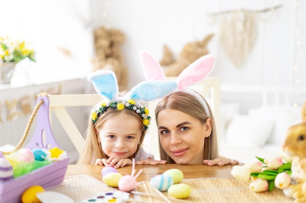 mãe de Páscoa e filha pequena com orelhas de coelho em sua cabeça estão se preparando para o feriado por se divertir brincando e passar tempo juntos ovos coloridos estilo de vida