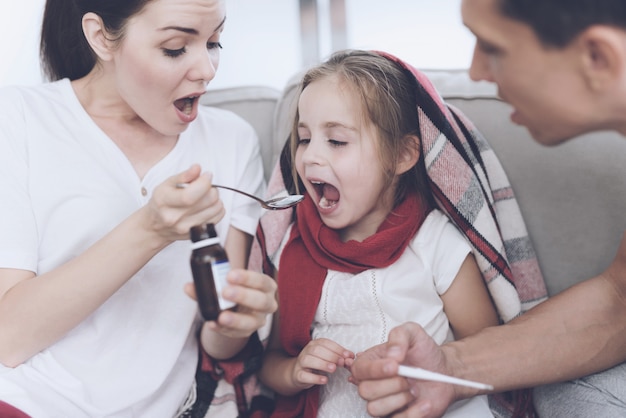 Mãe derrama uma xarope de menina em uma colher