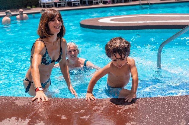 Mãe e avó se divertindo com o neto na piscina nas férias de verão curtindo a água