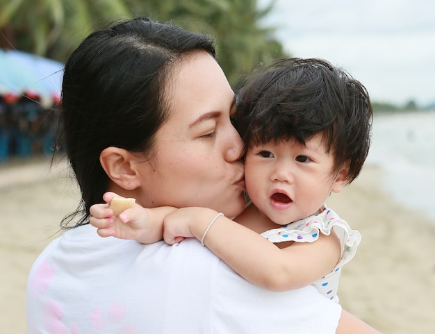 Mãe e bebê beijando e abraçando. família feliz na praia