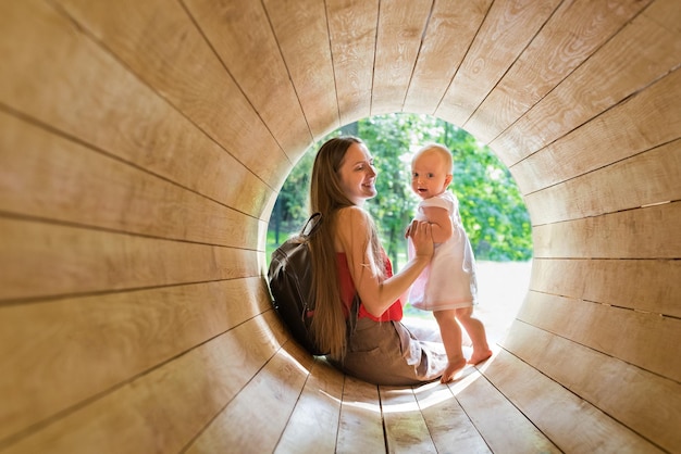 Mãe e bebê brincando no Playground no túnel de madeira Ecofriendly playground natural