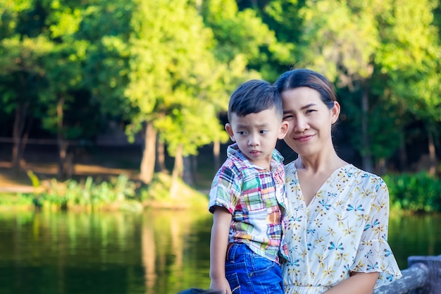 Foto mãe e bebê estão felizes, sorrindo, apreciando o ar quente e puro em um belo jardim.