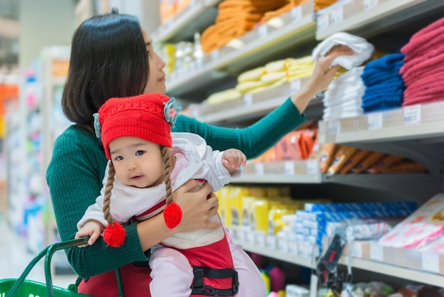 Mãe e bebê fazendo compras no supermercadoA mulher tailandesa tem uma filha