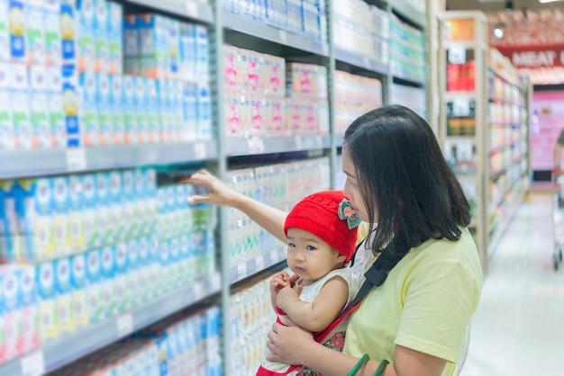 Mãe e bebê fazendo compras no supermercadoA mulher tailandesa tem uma filha