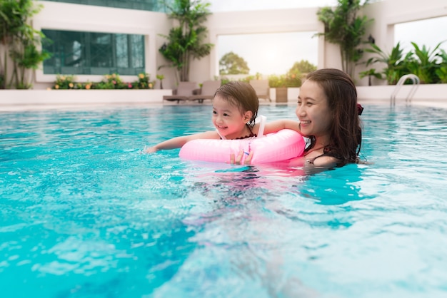 Mãe e bebê menina se divertindo na piscina. Férias de verão e conceito de férias