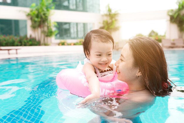 Mãe e bebê menina se divertindo na piscina. Férias de verão e conceito de férias