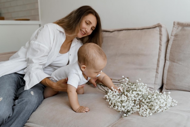 mãe e bebê na cama com um buquê de flores brancas