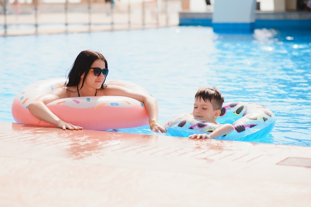 Mãe e bebê na piscina do resort tropical. mãe e filho brincando na água.