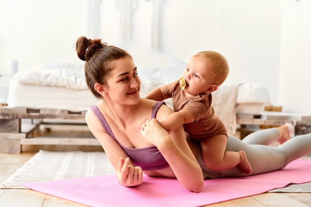 Mãe e bebê praticam esportes juntos O bebê engatinha nas costas da mãe