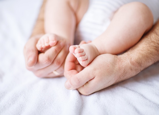 Mãe e bebê recém-nascido. Close-up da mão da mãe e do pé de um recém-nascido. Foto com espaço em branco para texto
