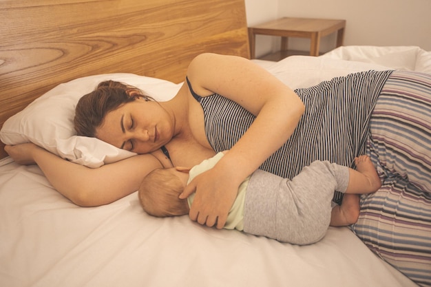 Mãe e bebê recém-nascido dormem na cama