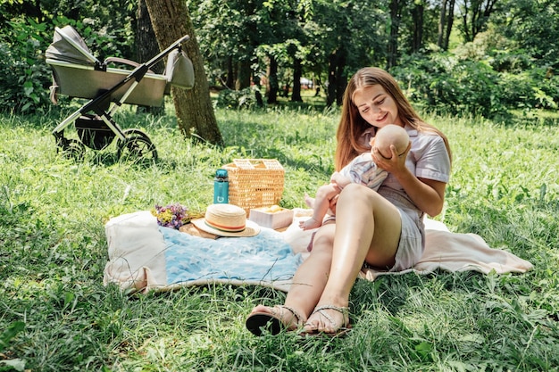 Mãe e bebê recém-nascido no carrinho no parque de verão Feliz jovem mãe cuidando do bebê no carrinho