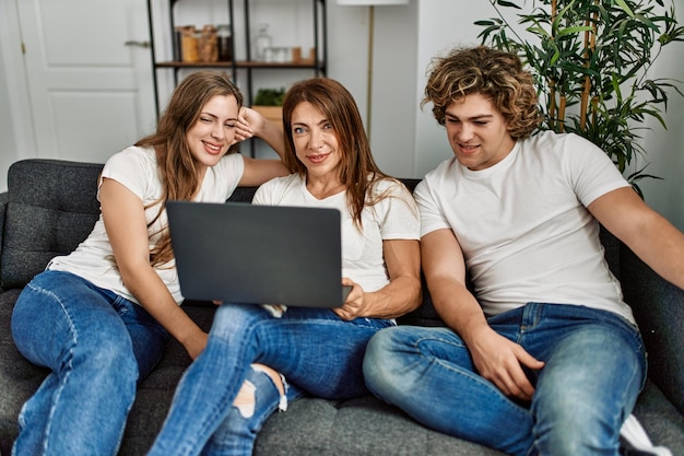 Mãe e casal usando laptop sentado no sofá em casa