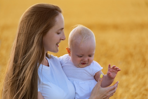 Mãe e criança linda jovem fora. Retrato mãe e bebê no espaço amarelo neutro