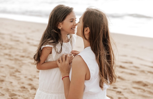 Mãe e filha a tocar o nariz na praia.