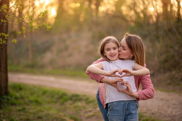 Mãe e filha abraçam e mostram um coração com as mãos Dia das mães