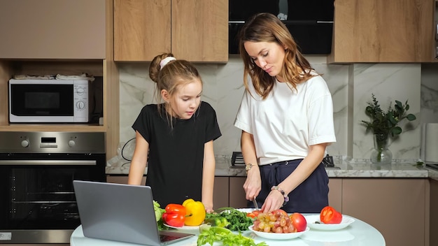 Mãe e filha adolescente assistem receita de salada no laptop