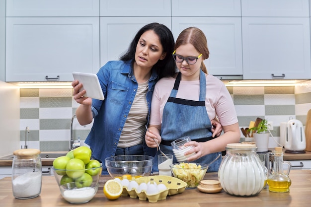 Mãe e filha adolescente preparando torta de maçã juntos