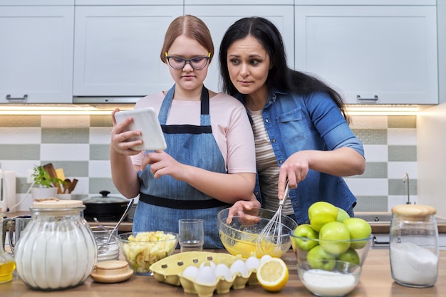 Mãe e filha adolescente preparando torta de maçã juntos