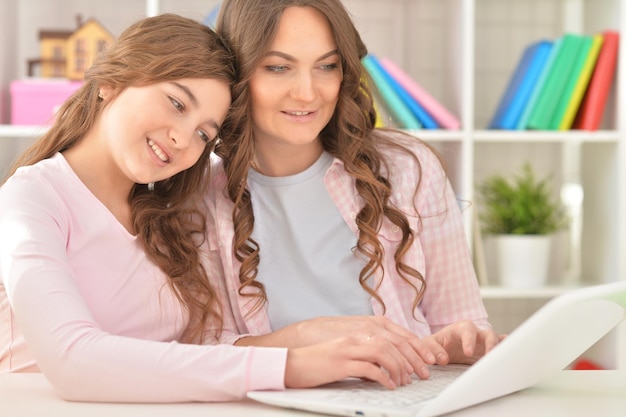 Mãe e filha adolescente usando laptop em casa