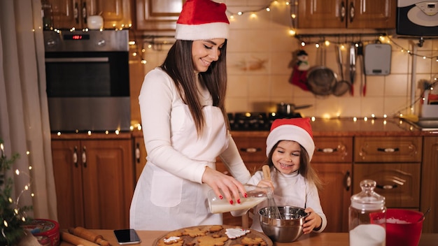 Mãe e filha adorável passam um tempo na cozinha em vésperas de Natal preparando doces para