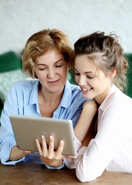 Foto mãe e filha adulta usando computador tablet em casa