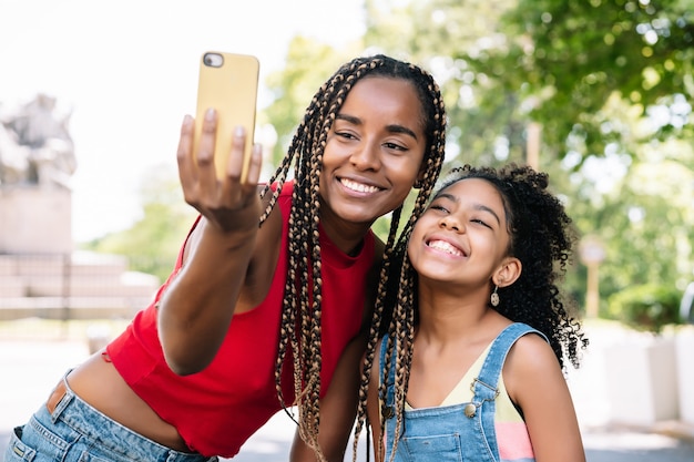 Mãe e filha afro-americanas curtindo um dia ao ar livre enquanto tiravam uma selfie