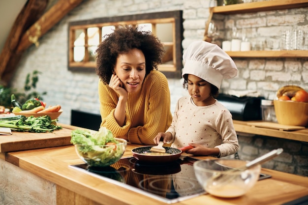Mãe e filha afro-americanas preparando refeição na cozinha