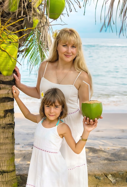 Foto mãe e filha bebem coco na praia