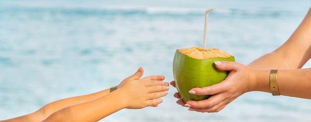 Mãe e filha bebem coco na praia