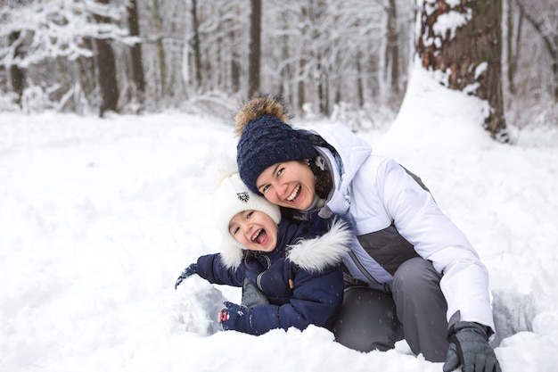 Mãe e filha brincam de neve, constroem uma fortaleza, fazem bolas de neve. Férias de inverno