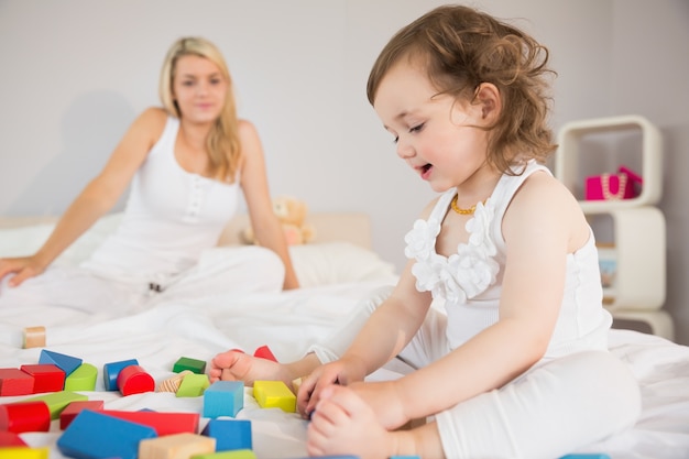 Mãe e filha brincando com blocos de construção na cama