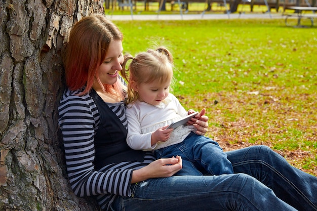 mãe e filha brincando com smartphone