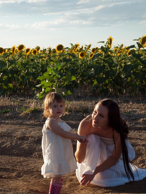 Mãe e filha brincando no campo de girassol.