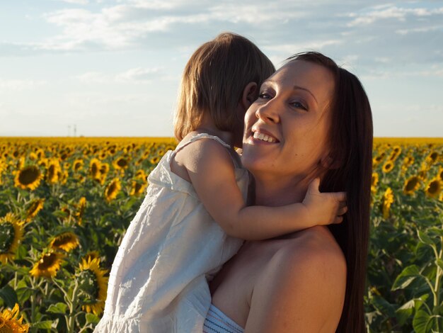 Mãe e filha brincando no campo de girassol.