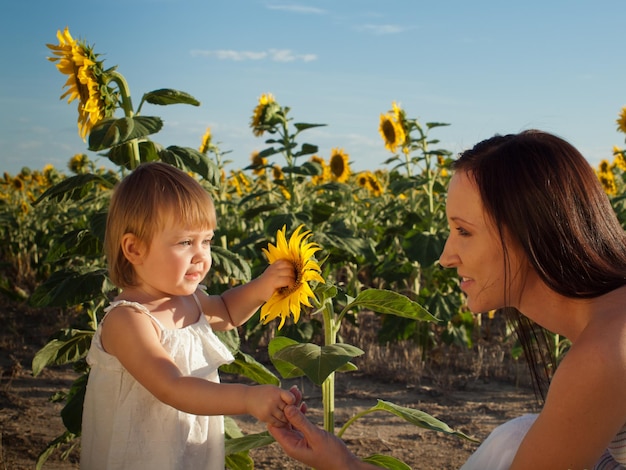 Mãe e filha brincando no campo de girassol.