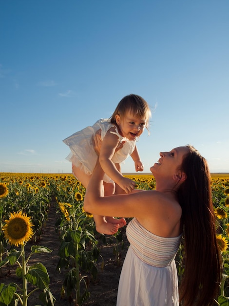 Mãe e filha brincando no campo de girassol.