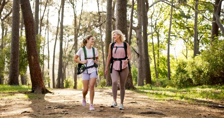 Foto mãe e filha caminhando na floresta com rir para fitness aventura passeios e explorar a natureza mochila mulher madura e menina na floresta con caminhadas viagens de férias e ligação com piada