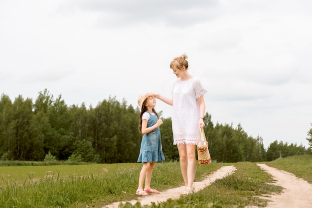 Mãe e filha caminhando na floresta e de mãos dadas.