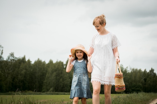 Mãe e filha caminhando na floresta e de mãos dadas.