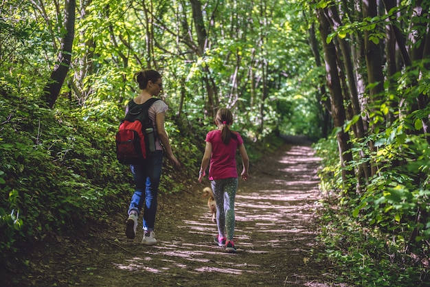 Mãe e filha caminhando no caminho na floresta