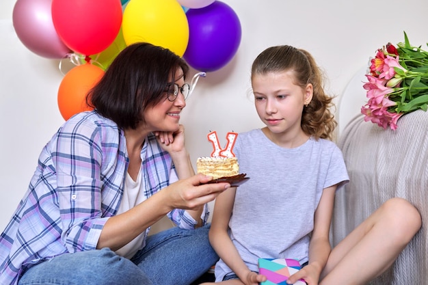 Mãe e filha com bolo de aniversário com balões de presente de velas