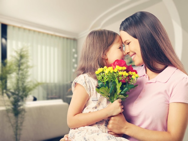 Mãe e filha com buquê de flores contra fundo desfocado verde.