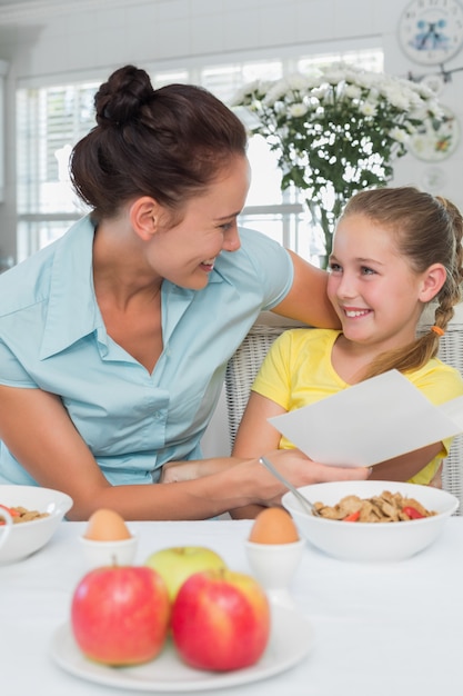 Mãe e filha com cartão na mesa de café da manhã